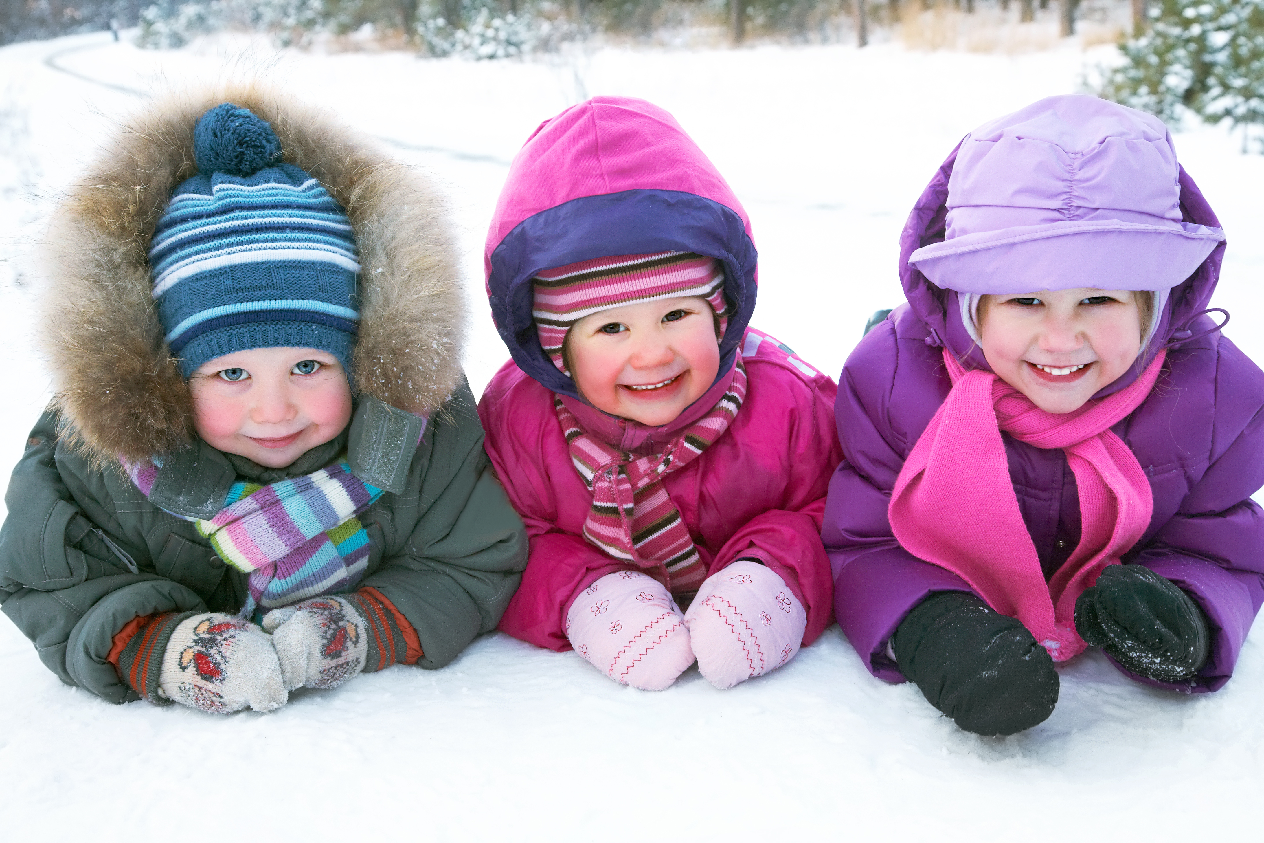 Kids laying in snow smiling