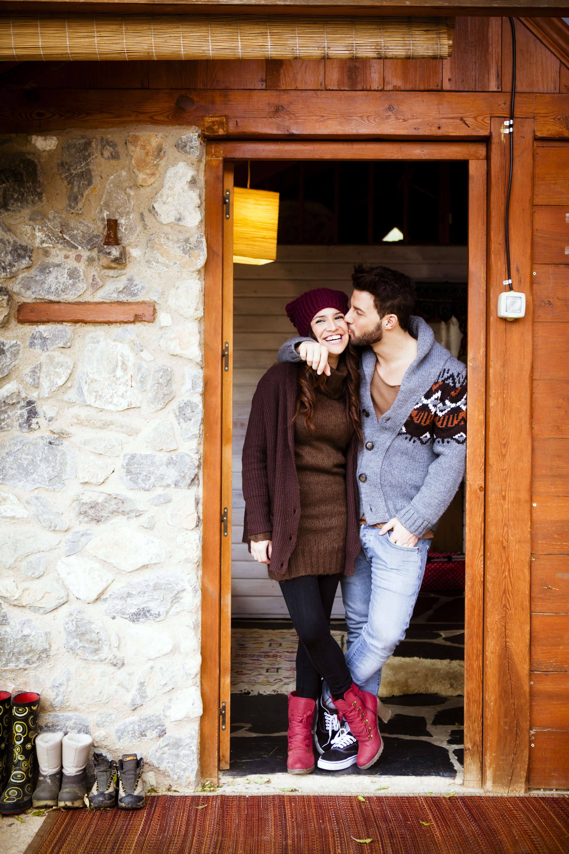 Couple standing in the cabin door with the guy kissing the girl on cheek